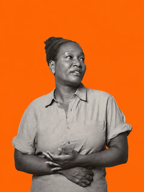 An independent store owner in a linen shirt, editorial portrait on an orange backdrop