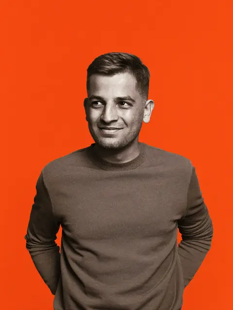 A software marketing lead in a knit sweater, editorial portrait on an orange backdrop